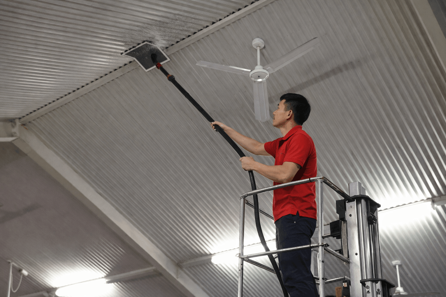 Nhân viên MCX Clean vệ sinh trần nhà xưởng bằng thiết bị chuyên dụng trên xe nâng